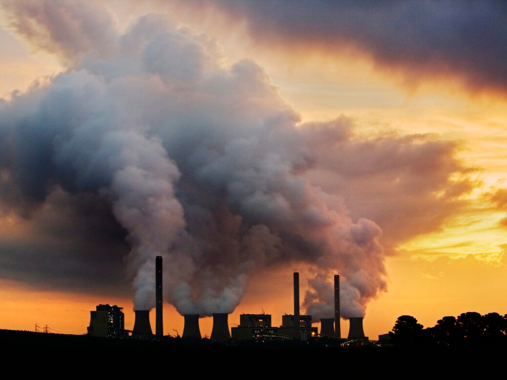 Power plant emitting steam and smoke at sunset.